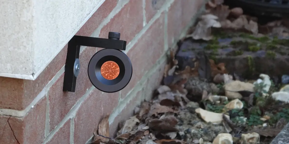 Monitoring survey prism mounted on a brick wall, used to track structural movements and ensure stability.
